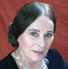 Porträt-Foto der Autorin und Illustratorin Alona Frankel, Haare nach hinten hochgesteckt, im schwarzen Oberteil mit Perlenkette vor rotem Hintergrund