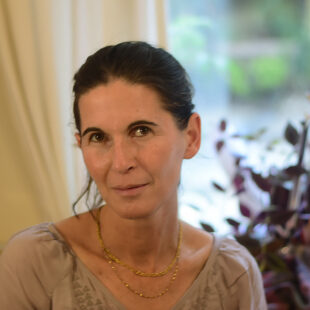 inbal_Leitner_Foto_privat Porträt der Illustratorin Inbal Leitner, Mit dunkel-braunen Hochgesteckten Haaren, eine goldene Kette um den Hals und eine beige Bluse mit V - Ausschnitt tragend.